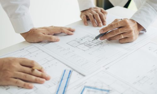 Team architect or engineering people discussion working on table together at a construction site.